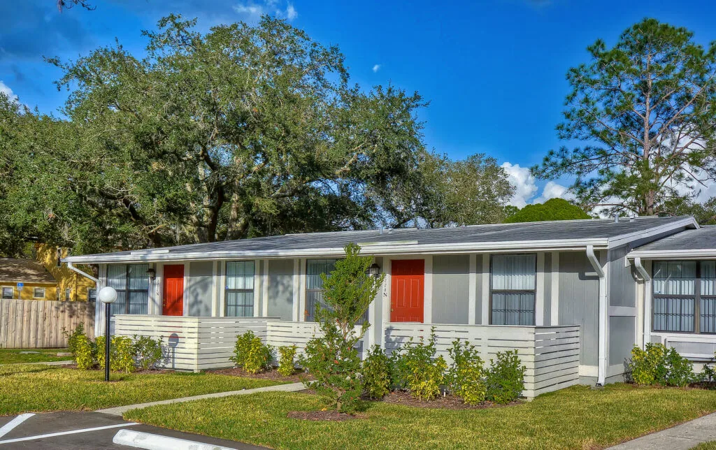 Apartment buildings with red entry doors and private patios at Live Oak Apartments in Tampa, Florida.